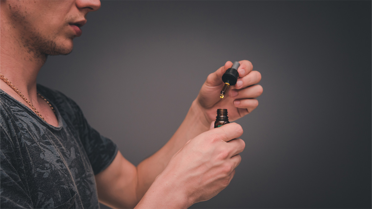 A man holding a CBD oil bottle to take his dose.
